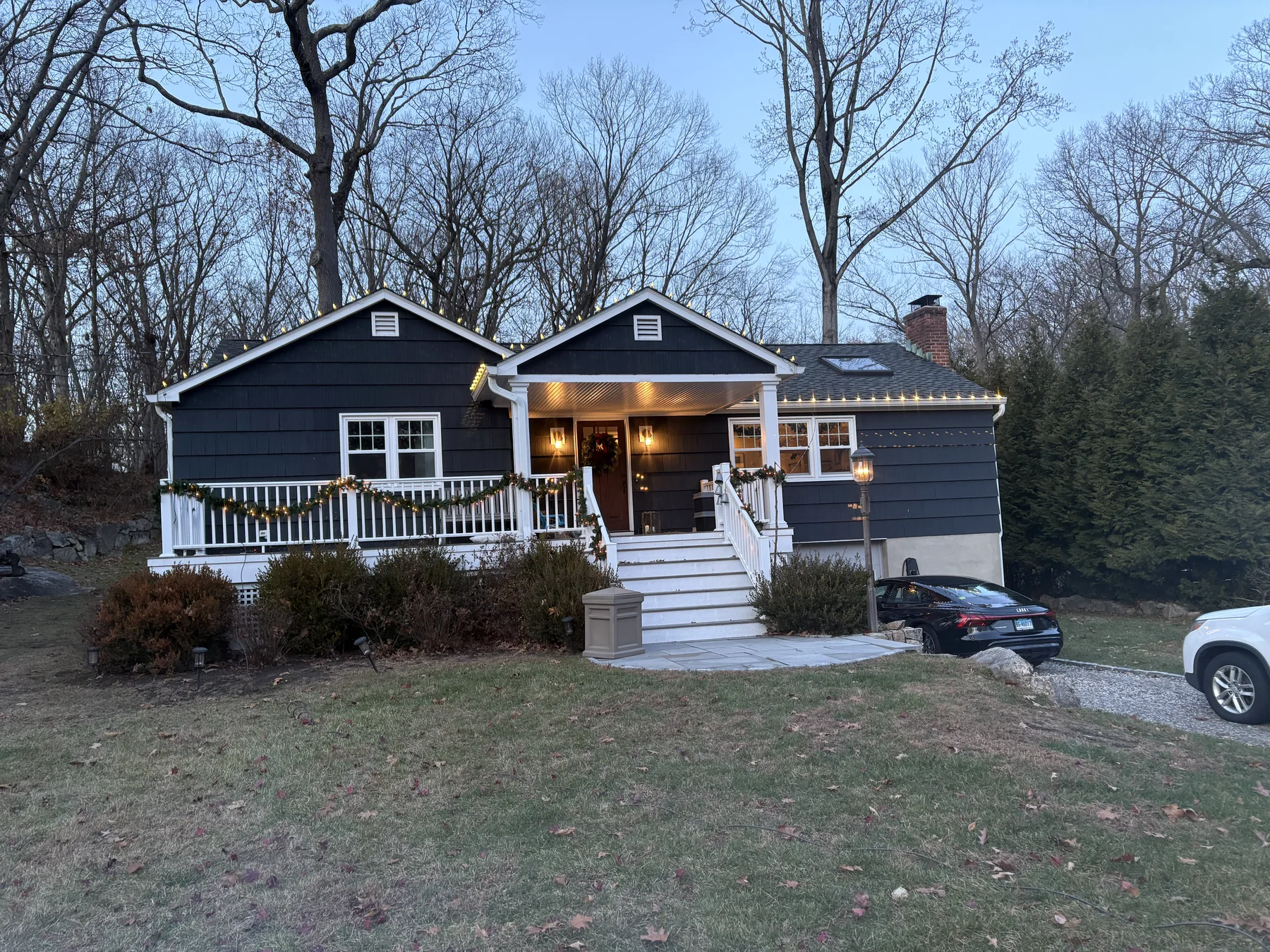Holiday lighting on a porch and roofline at dusk
