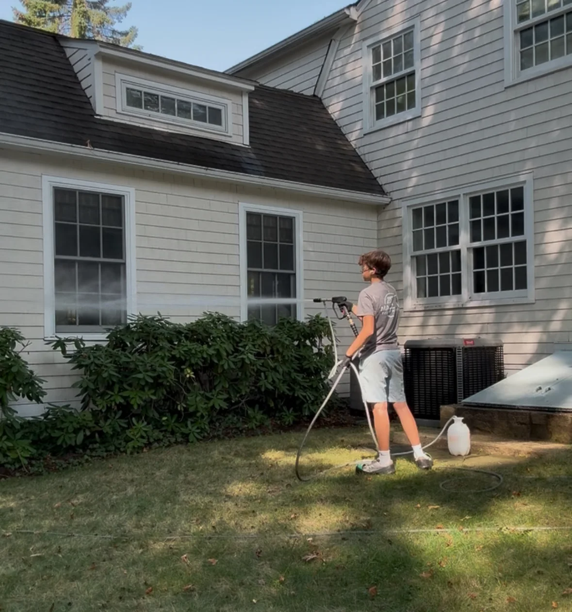 Technician soft washing the side of a house