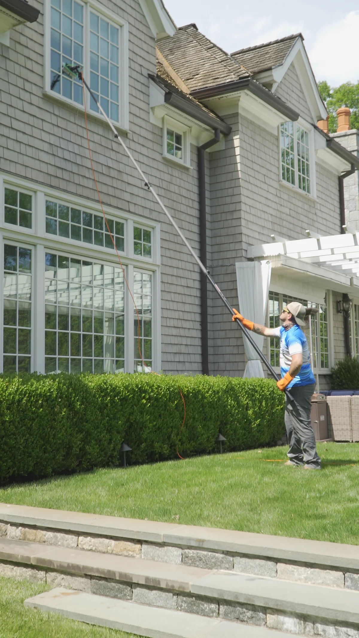 Cleaning windows on a shingle-style home